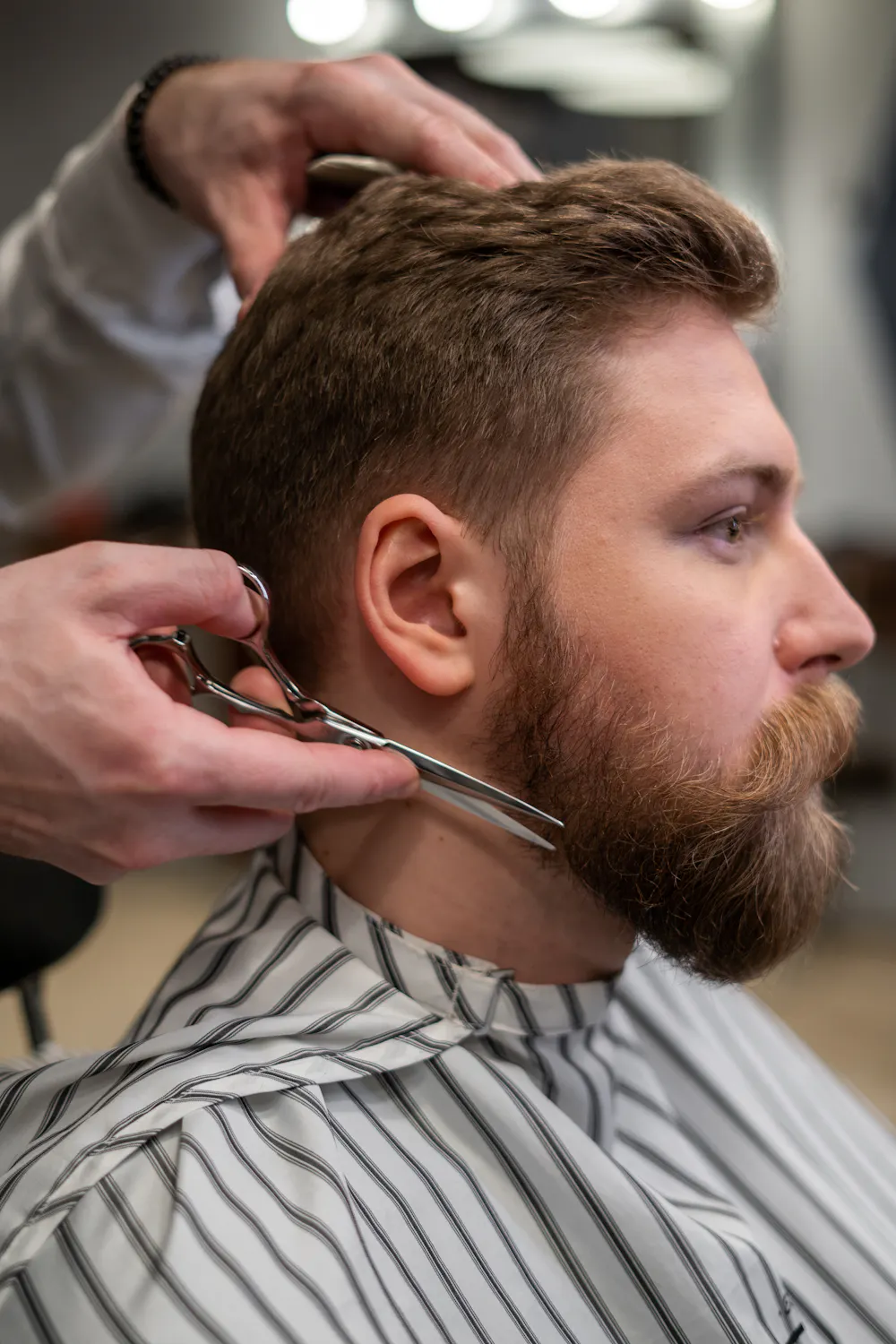 Barber cutting hair in modern barbershop